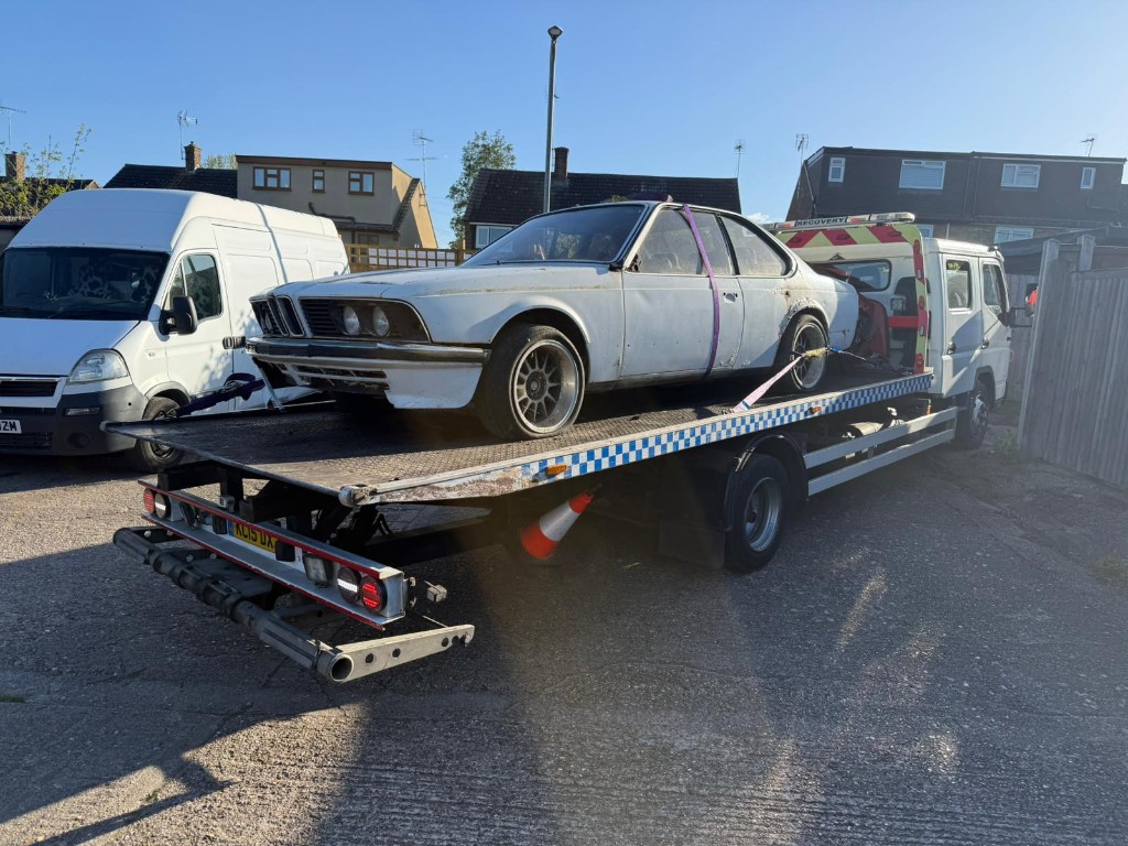 Classic white BMW coupe secured on flatbed truck